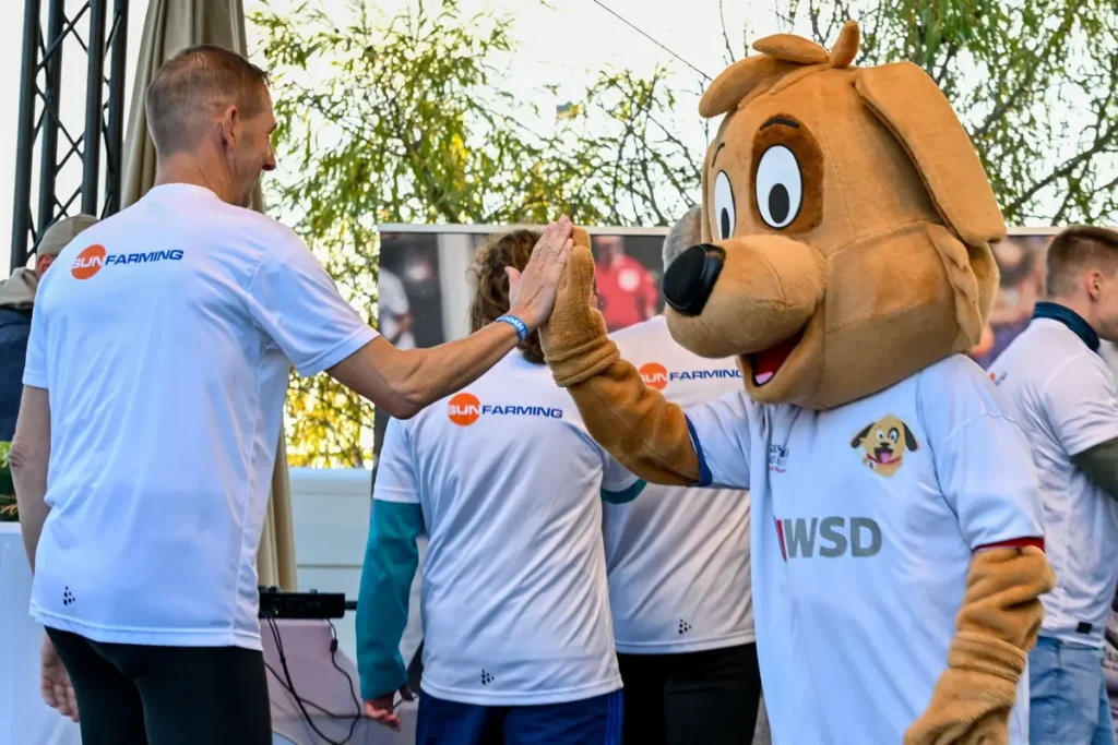 Maskottchen klatscht mit einem Mitglied des Sponsoren-Teams ab