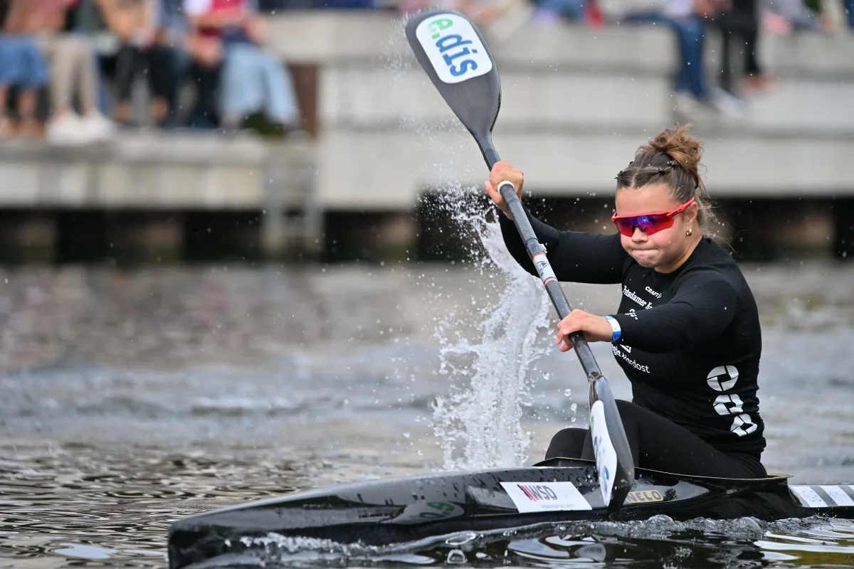 Kanutin mit Sonnenbrille im dunklen Boot beim Rennen