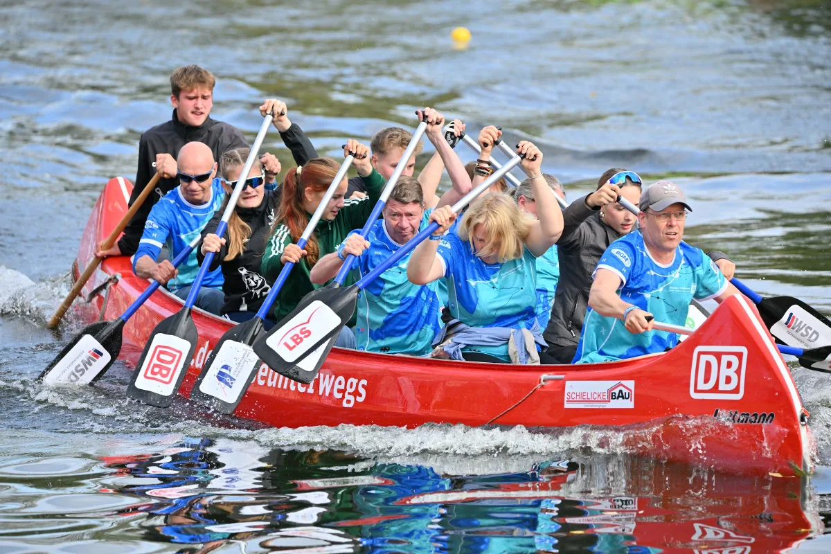 Rotes Drachenboot mit Team in blauen Trikots im Rennen