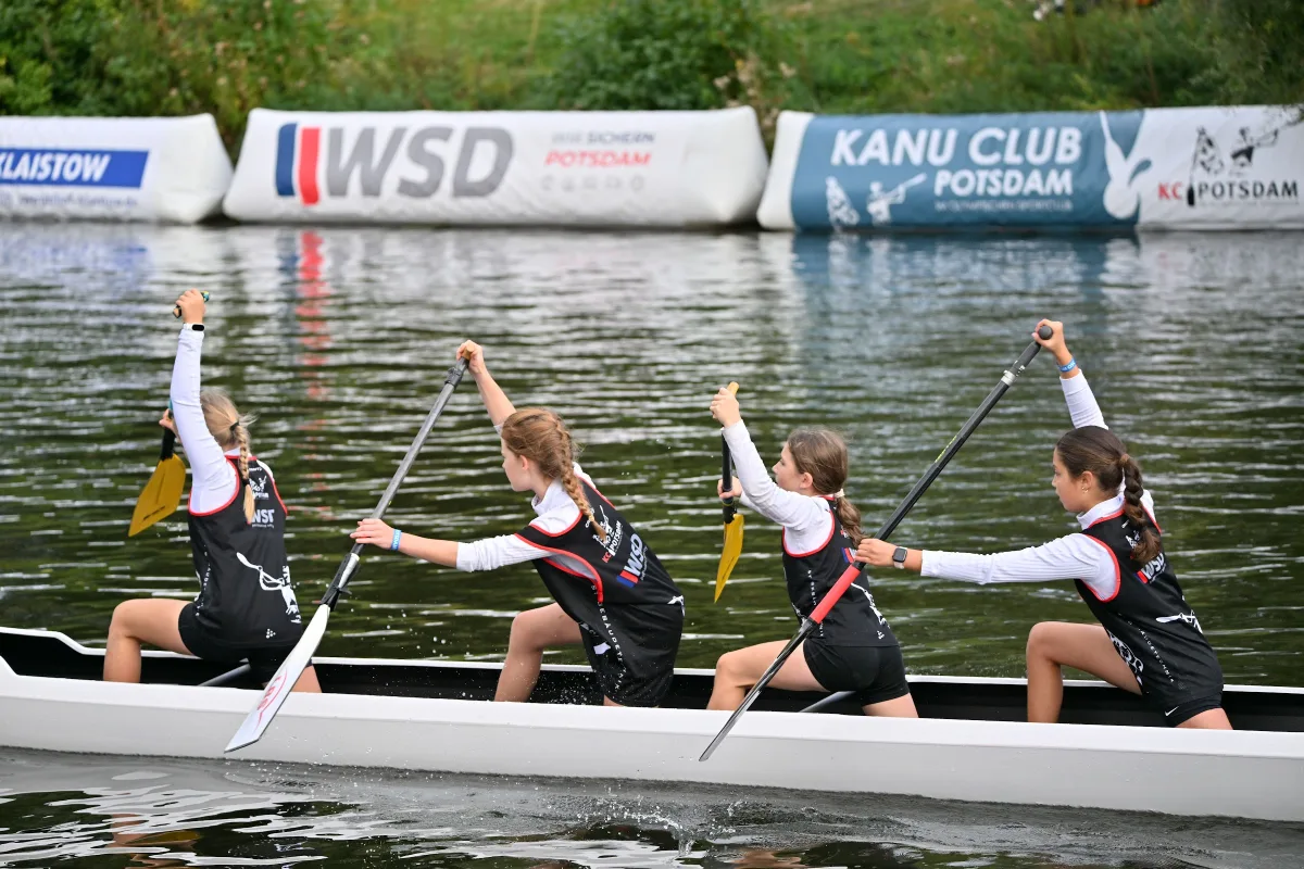 Kinder paddeln gemeinsam im weißen Boot beim Kinderrennen