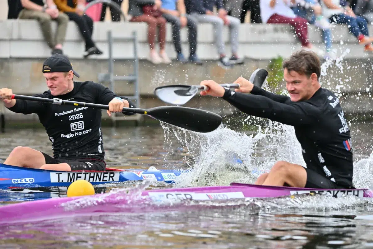 Zwei Kajaks nebeneinander mit Wasserspritzern vor dem Publikum